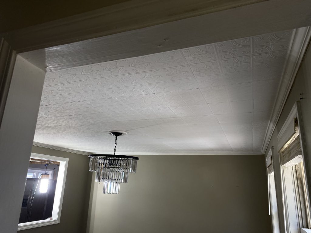 Decorative ceiling with chandelier in an interior room Interior room with decorative plaster ceiling, crown molding, and chandelier installation